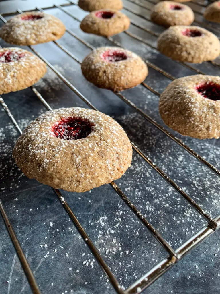 Vollwertige Engelsaugen oder Husarenkrapfen mit Vollkorn-Dinkelmehl und Vollrohrzucker Marmeladenplätzchen mit Puderzucker liegen auf Rost